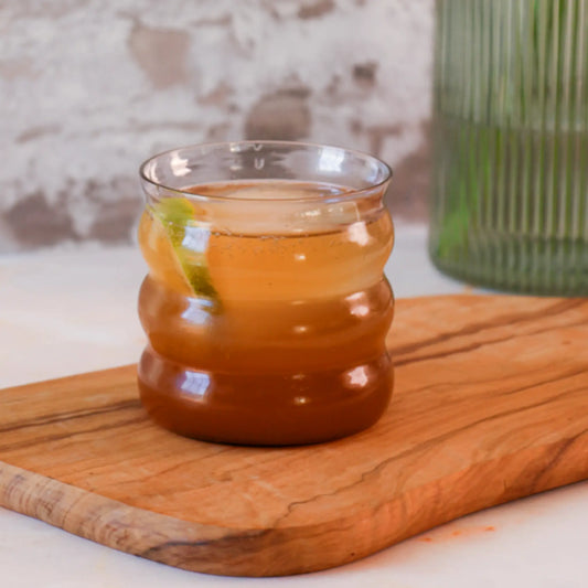 Spice Mule mit unserem Chai Konzentrat – erfrischender Chai Cocktail mit Limette, serviert im Glas auf Holzbrett. Ein spritziger Drink mit würziger Chai-Note – perfekt für Brunch oder Sundowner.